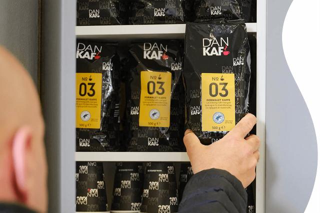 DanKaf-konsulent fylder op i skab med frisk kaffe